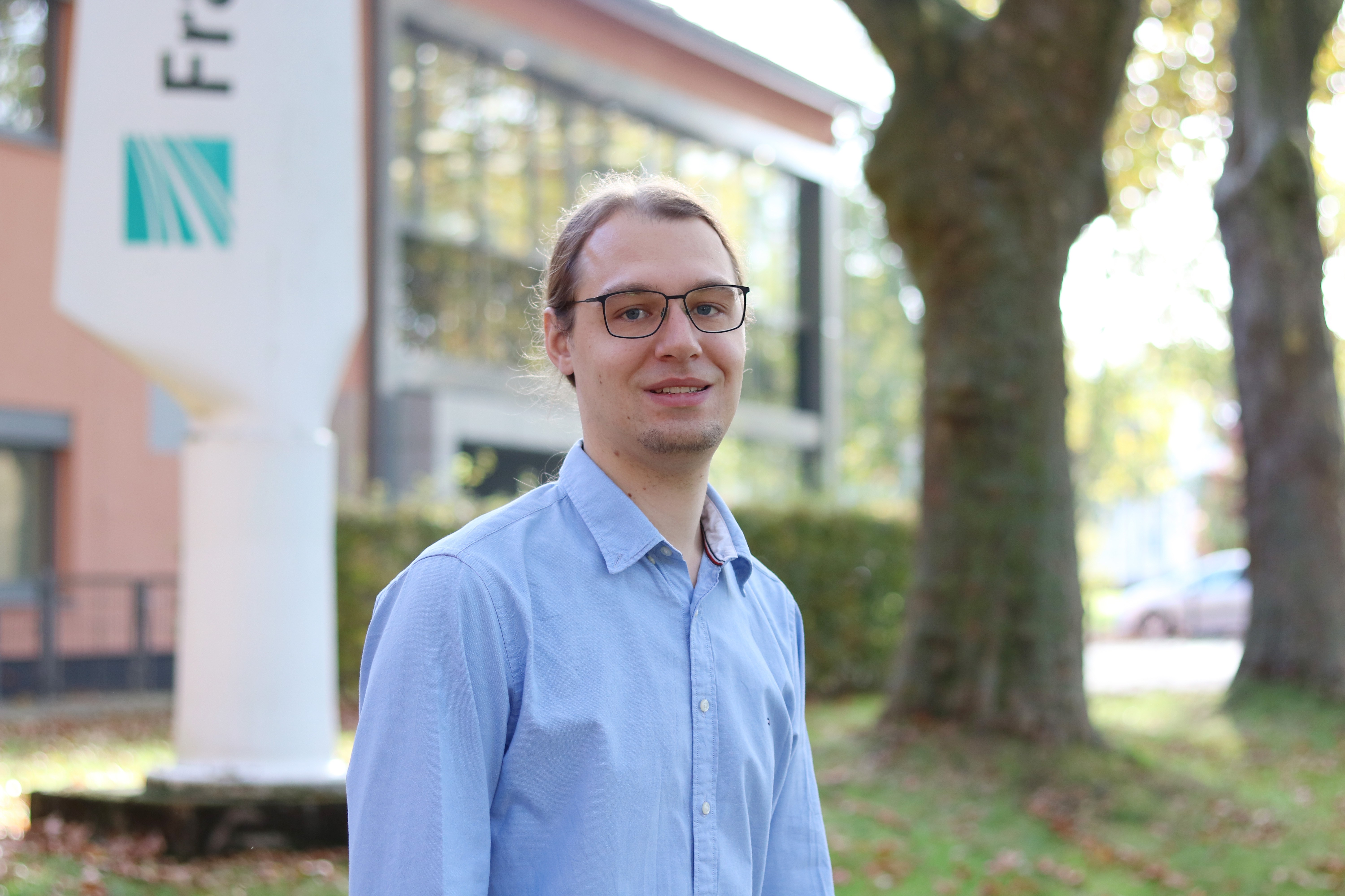 Dr. Nils Jonas Ziegeler steht vor einem Gebäude und guckt in die Kamera.